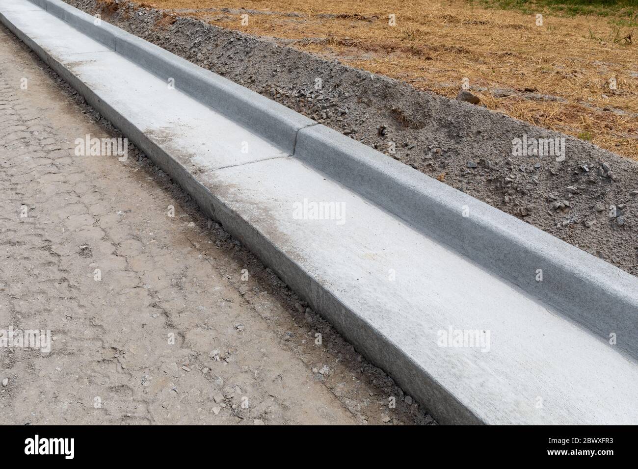 Straßenbau Details, extrudierte Beton Bordstein neben frisch präparierten Straßenbett, horizontale Aspekt Stockfoto