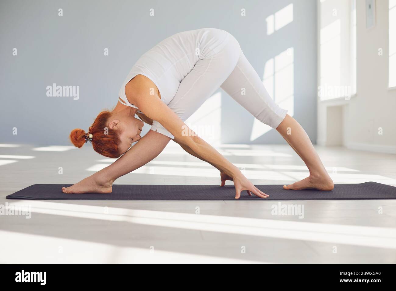 Junge Frau, die Yoga im Vorwärts biegenden Asana praktiziert Stockfoto