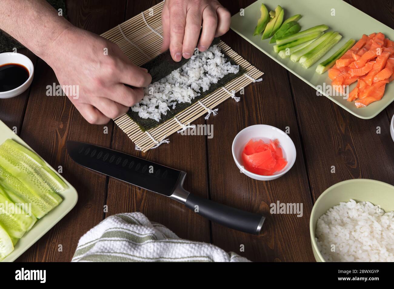 Sushi-Brötchen mit Reis, Lachs, Avocado, Gurke und Nori zu Hause kochen. Homemeade Essen. Hausmannskost Stockfoto