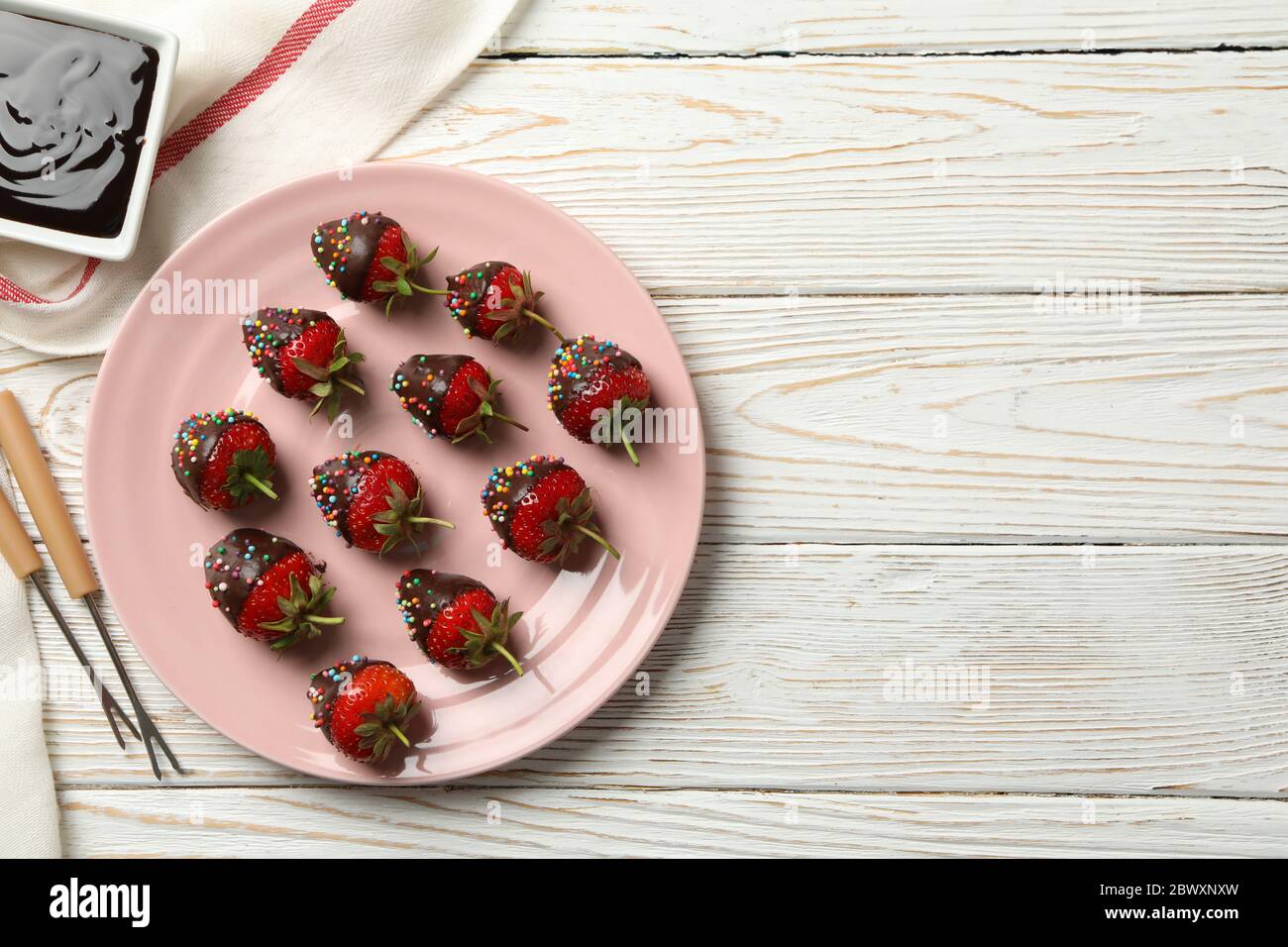 Schokoladenfondue. Erdbeere in Schokolade auf weißem Holzhintergrund Stockfoto