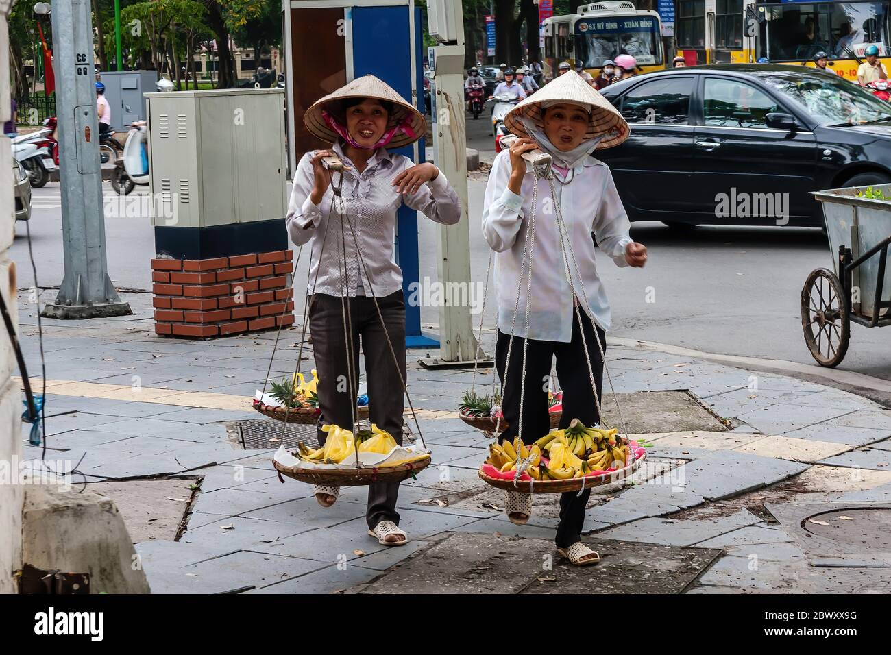 Vietnamesische Frauen mit Trageröcken Bananen zum Verkauf zu transportieren, Hanoi Stockfoto