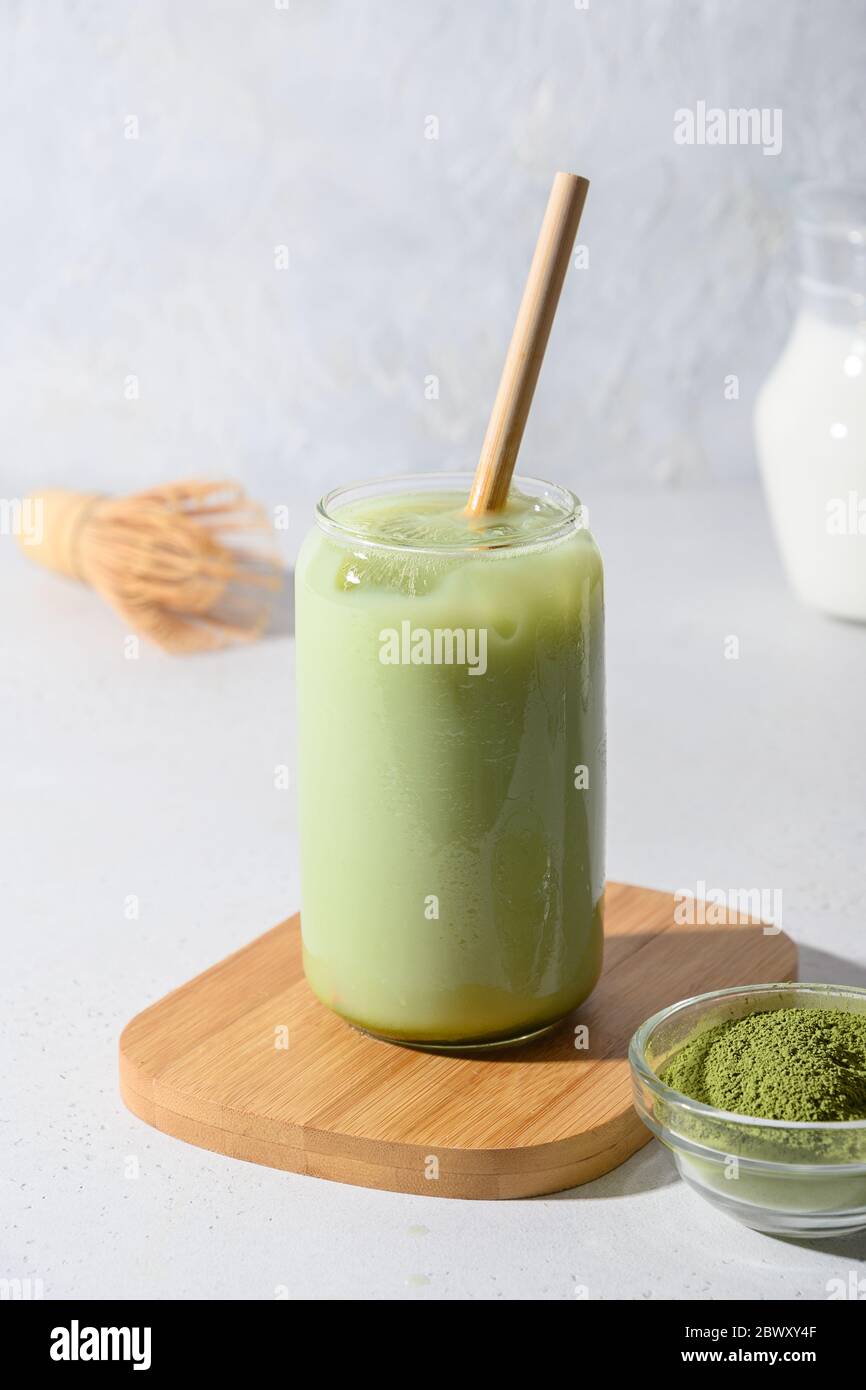 Iced Green Matcha Latte Tee im Glas auf weißem Hintergrund. Nahaufnahme. Vertikales Format. Stockfoto