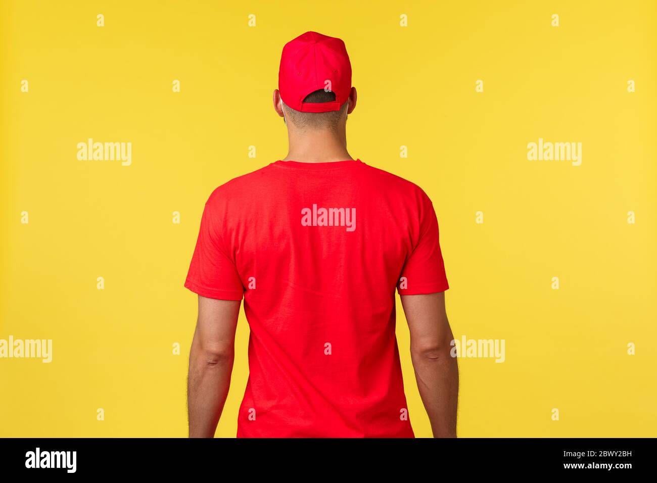 Express-Lieferung während der Pandemie, covid-19, sicherer Versand, Online-Shopping-Konzept. Rückseite des Kuriers trägt rote Uniform T-Shirt und Mütze, promo von Stockfoto