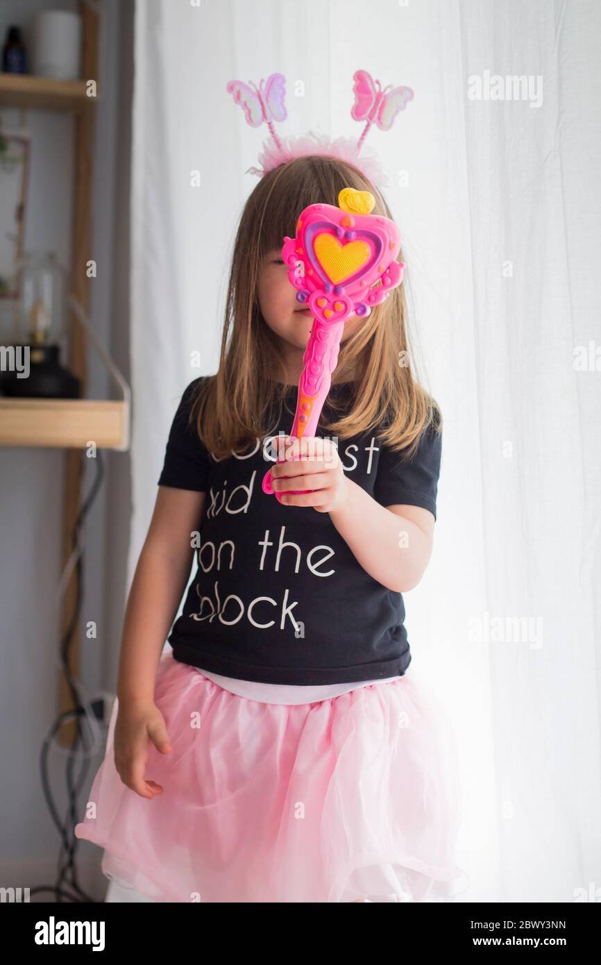 Kleines Mädchen, zu Hause in Verkleidung mit rosa Antennen und Tutu Rock,  hält ein Spielzeug Zauberstab, die ihr Gesicht. Gleichstellung der  Geschlechter und Stockfotografie - Alamy