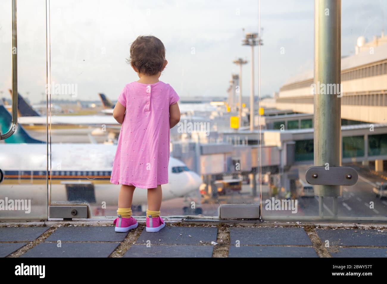 Das Kind schaut auf die Flugzeuge am Flughafen und wartet auf das Boarding. Rückansicht Stockfoto
