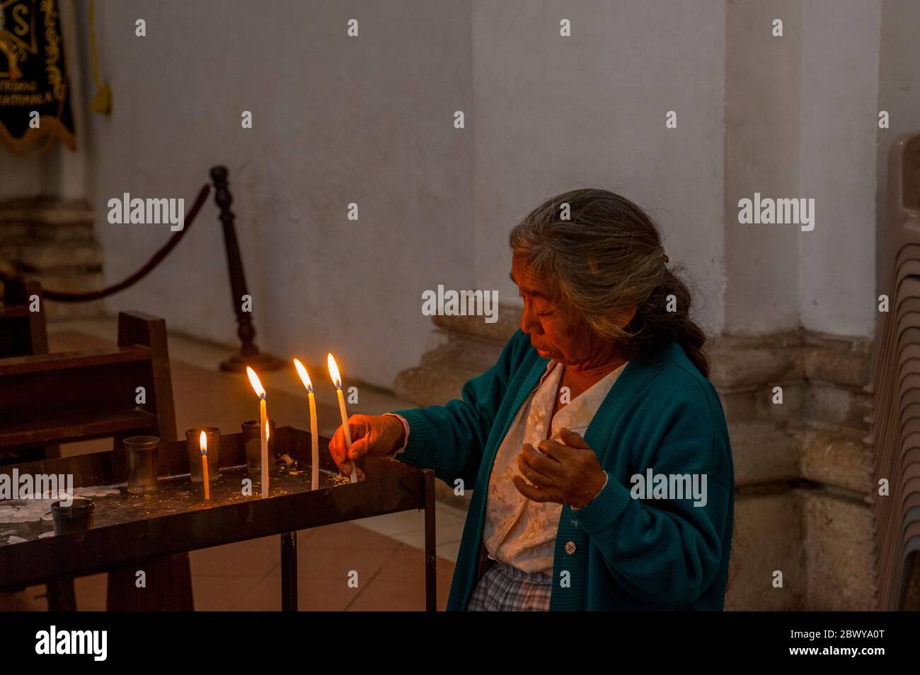 Eine Frau stellt Kerzen in der Kathedrale von Antigua Guatemala, einer römisch-katholischen Kirche in Antigua Guatemala, Guatemala, zur Verfügung. Stockfoto