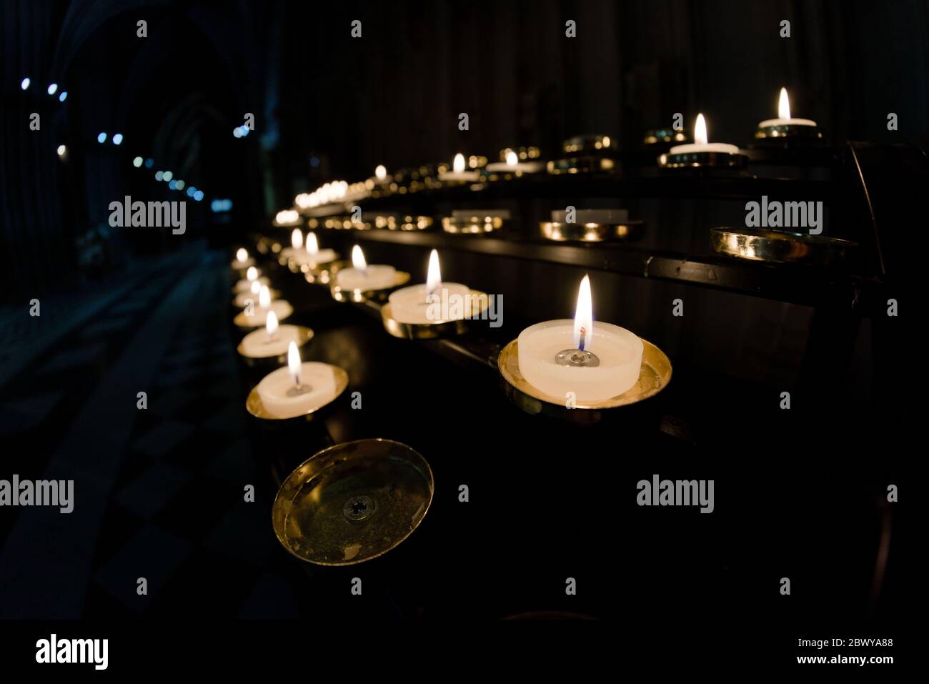 5 Reihen Gebetskerzen laufen von rechts nach links in diesem Weitwinkelfoto aus einer Kathedrale Stockfoto