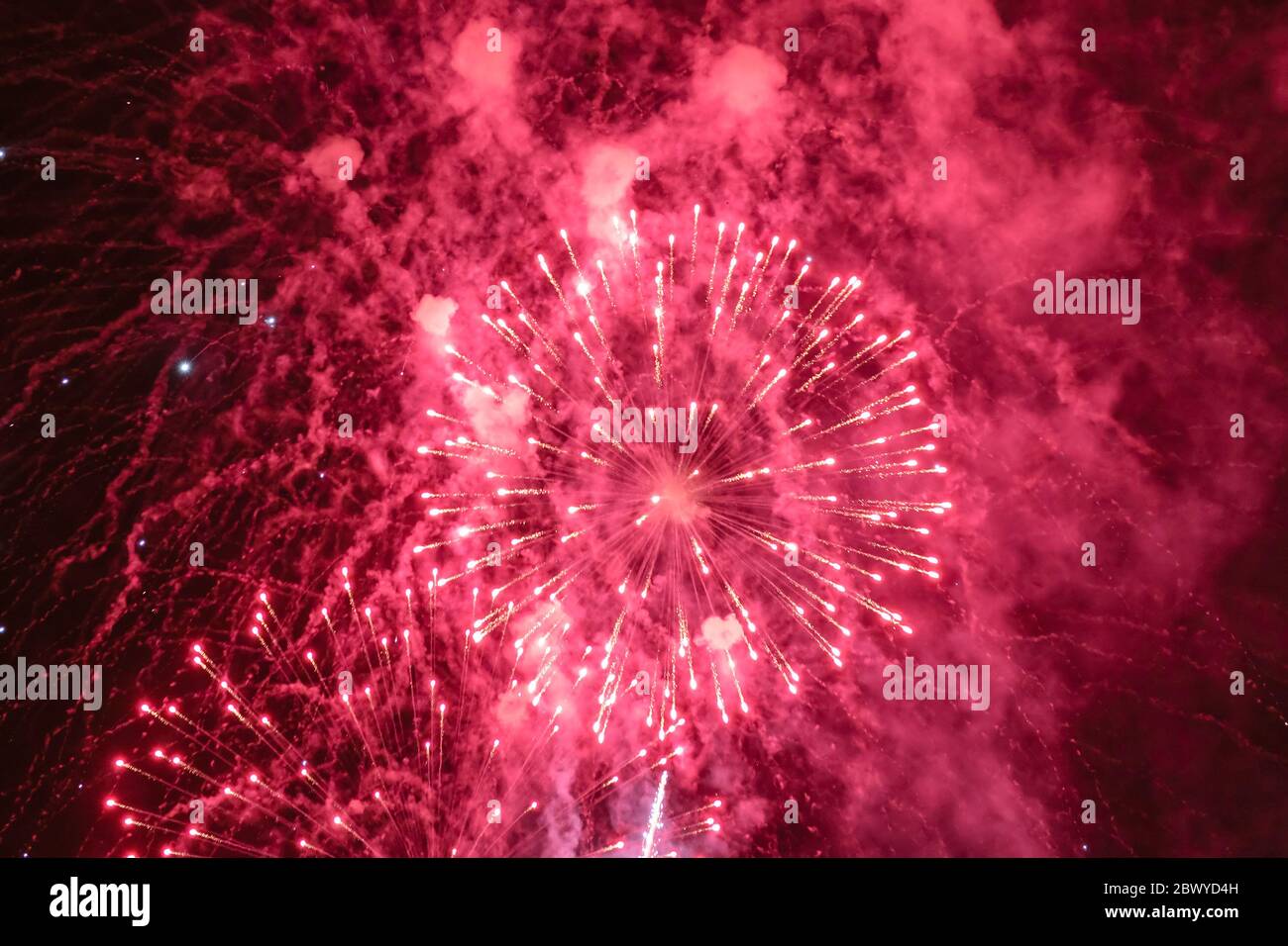 Rot-weißes Feuerwerk mit Rauch über dem schwarzen Himmel. Geringe Tastenbelichtung. Stockfoto