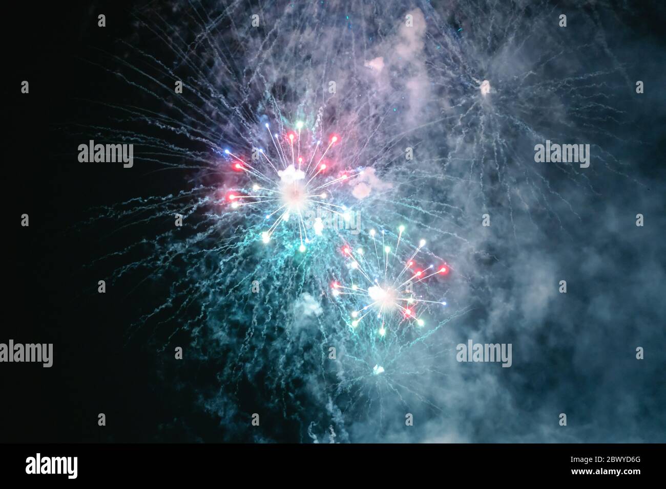Rot-weißes Feuerwerk mit Rauch über dem schwarzen Himmel. Geringe Tastenbelichtung. Stockfoto