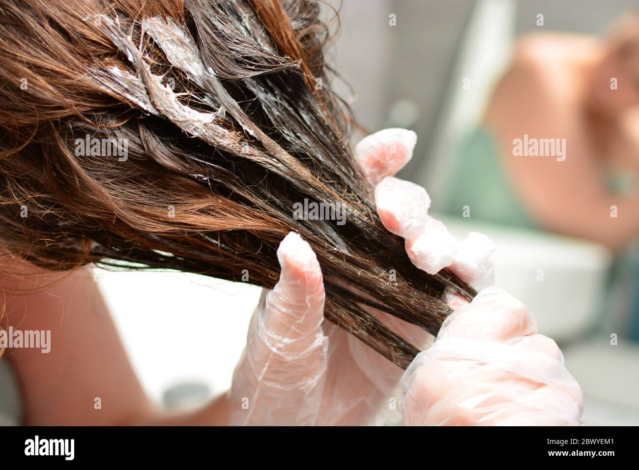 Junge Frau färbt ihr Haar zu Hause. Das Mädchen Färbung ihre Haare in ihrem eigenen Bad. Quarantäne, Haarpflege zu Hause bleiben Konzept. Stockfoto
