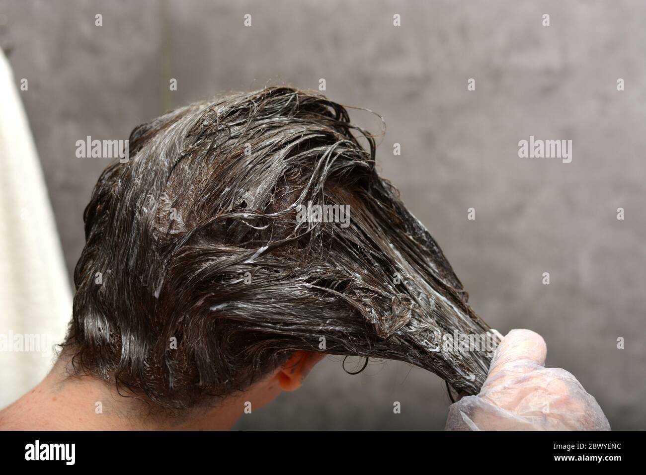 Junge Frau färbt ihr Haar zu Hause. Das Mädchen Färbung ihre Haare in ihrem eigenen Bad. Quarantäne, Haarpflege zu Hause bleiben Konzept. Stockfoto