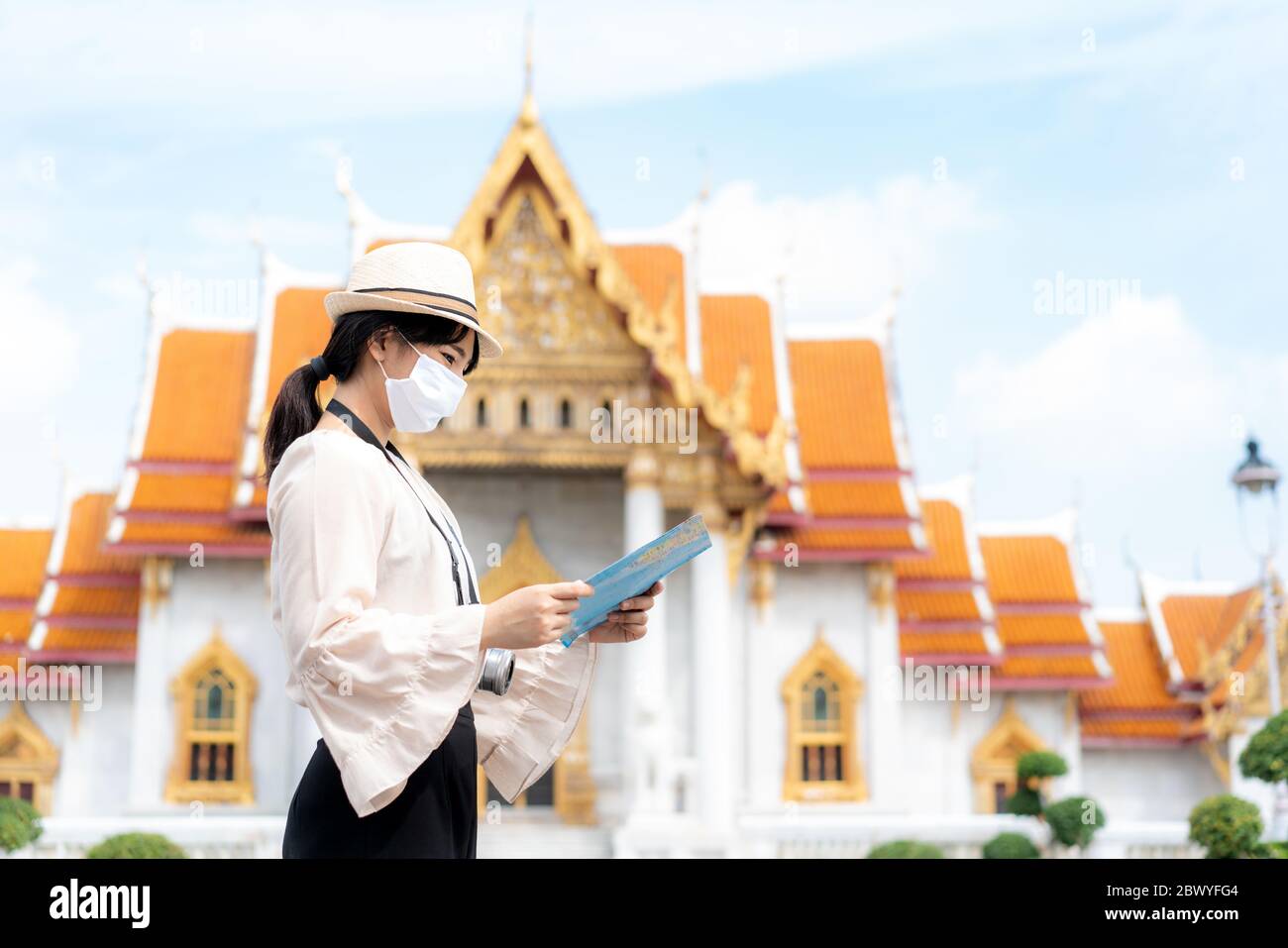 Asiatische Frau glücklich Touristen zu reisen mit Maske zum Schutz vor Covid-19 in ihren Ferien und sie auf der Karte in Tempel in Bangkok, Thailan Stockfoto