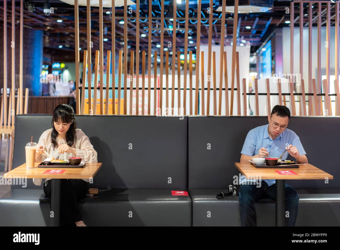 Asiatische Mann und Frau essen Essen auf dem Tisch von einer Person ein Tisch in Food Court für soziale Distanzierung 6 Füßlinge Konzept Schutz des Coronavirus Covid-1 Stockfoto