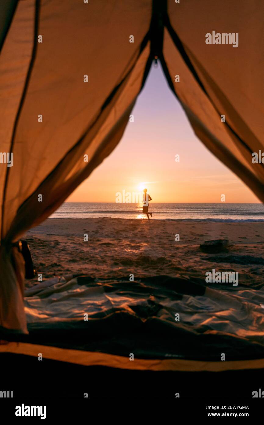 Blick durch die Tür öffnen von orange und grau Zelt Camping Sommer Strand Hintergrund am Morgen. Stockfoto