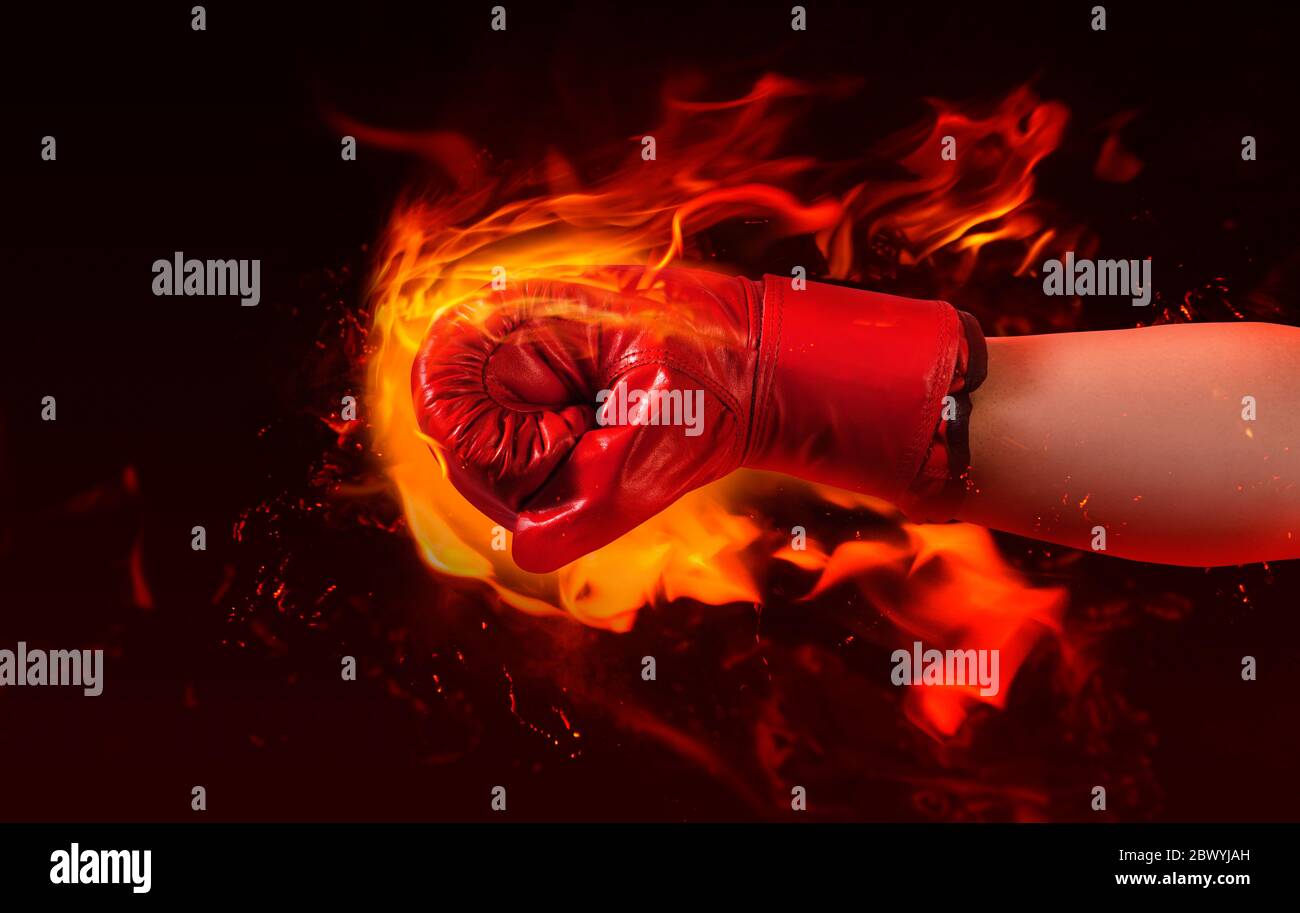 Foto von männlichen Hand in roten Boxhandschuh lochen Feuer auf brennendem Hintergrund. Stockfoto