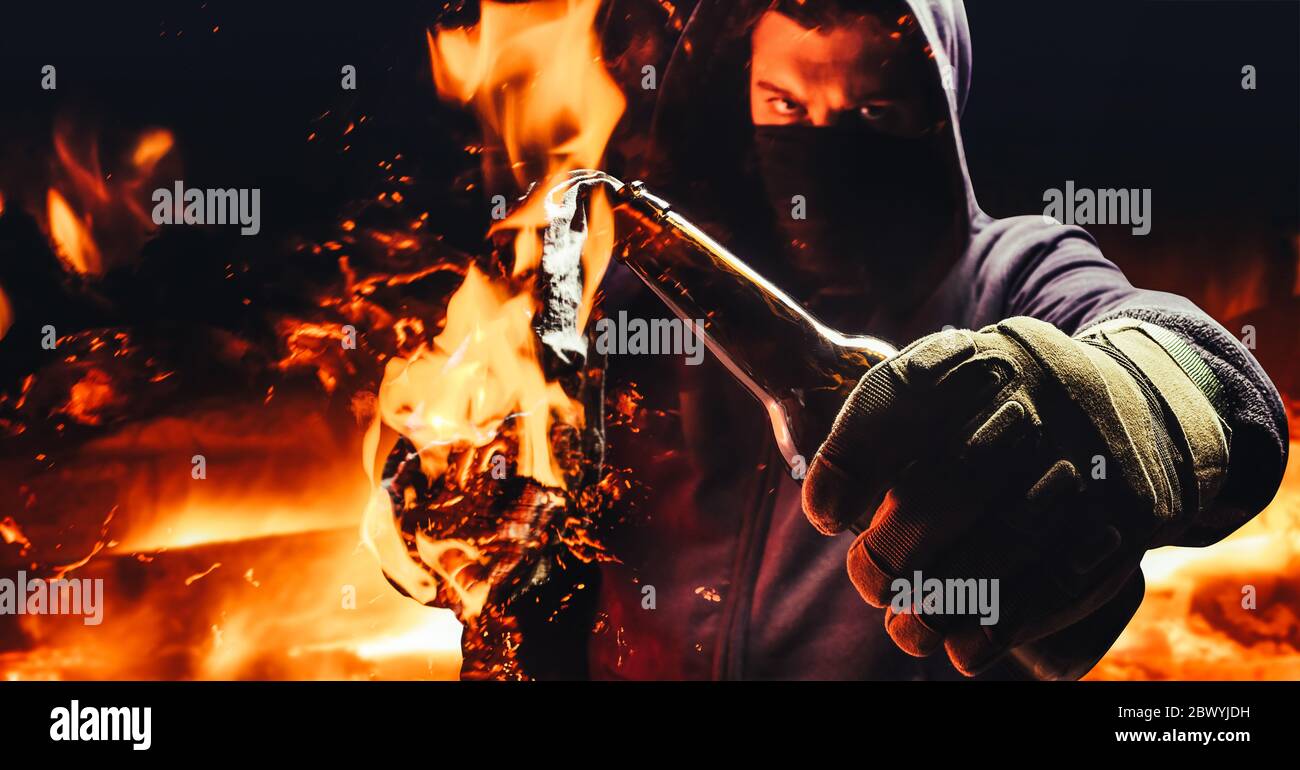 Foto eines Protestanten in Maske und Kapuze hält brennenden molotow-Cocktail  auf dunklem Feuer Hintergrund Stockfotografie - Alamy