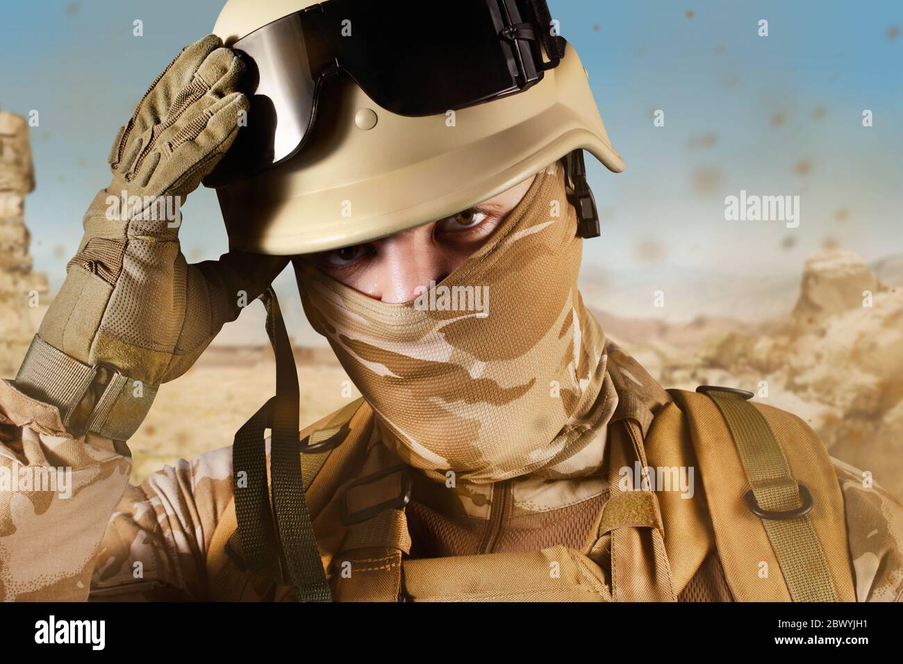 Foto eines voll ausgestatteten Wüstensoldaten im Helm auf Wüstenhintergrund. Stockfoto