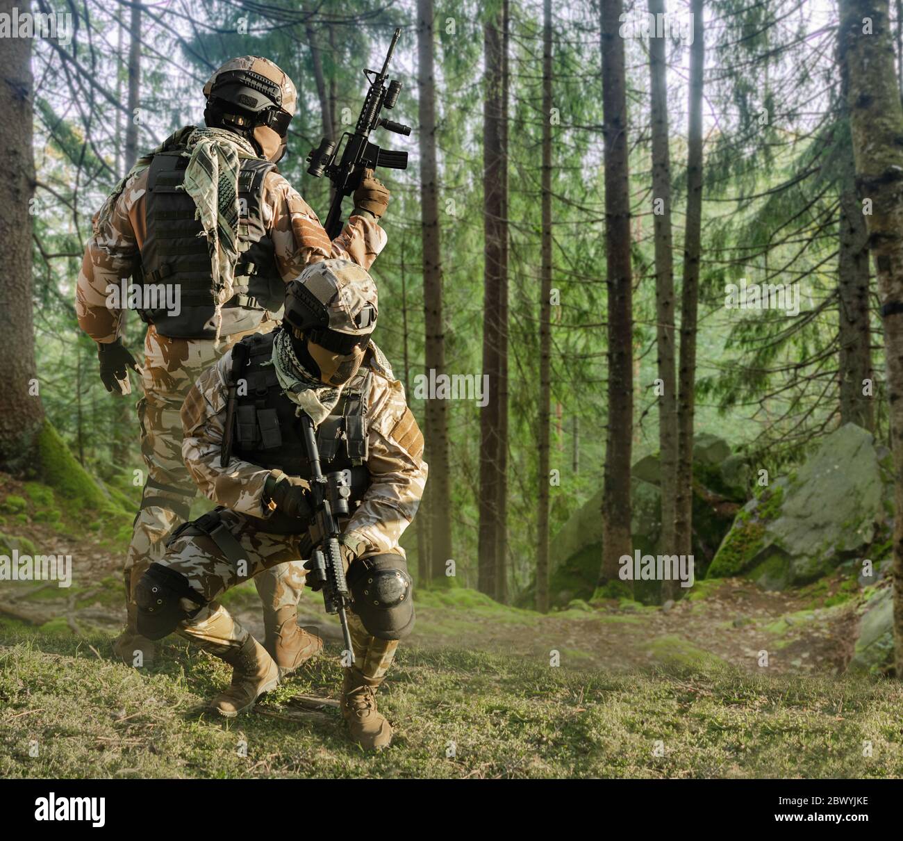 Foto von einem voll ausgestatteten Soldaten in Outfit, Rüstung, Helm, Brille mit automatischem Gewehr posiert auf Wald Hintergrund. Stockfoto