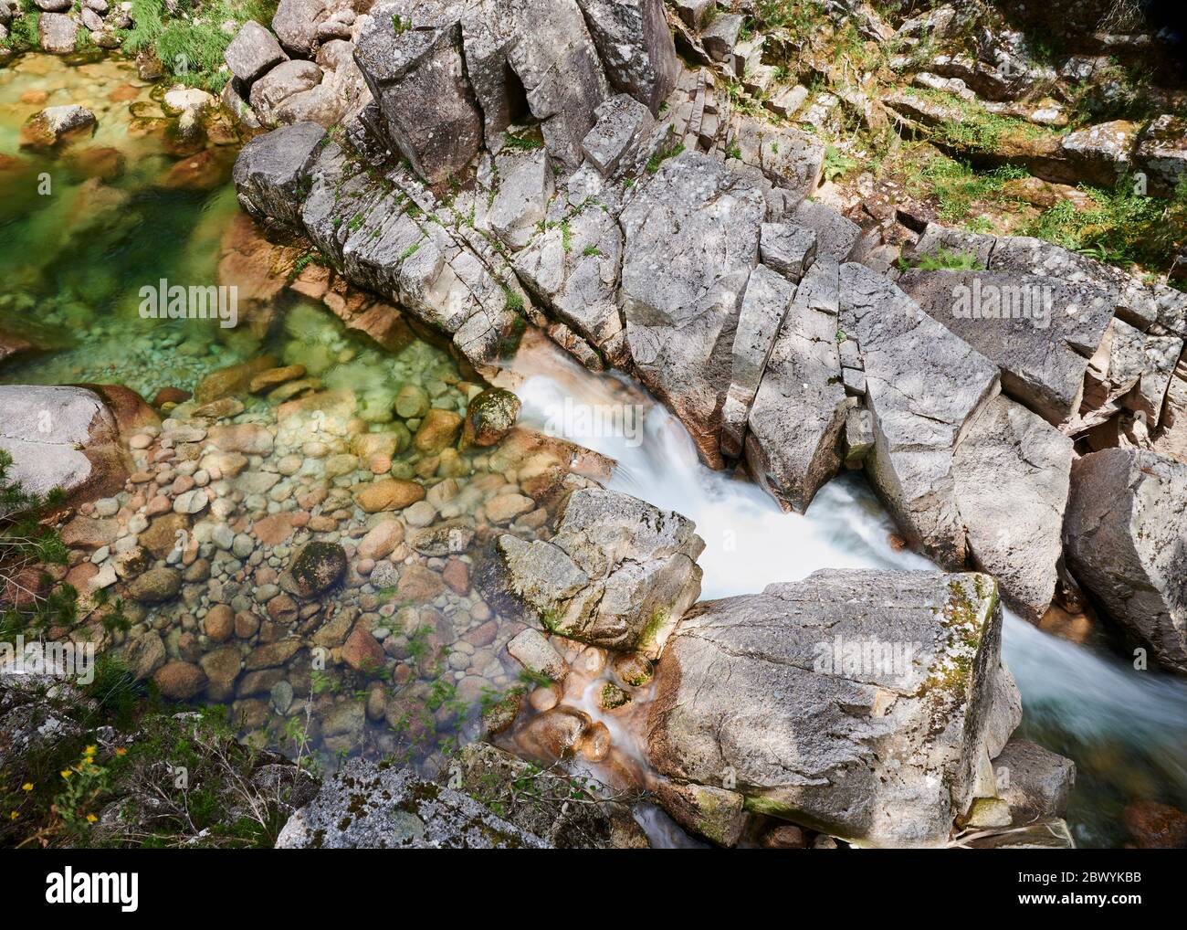 Wasserfall von Mata de Albergaria in der Mitte des Waldes fließt das Wasser die Felsen hinunter bis zum grünen See Stockfoto