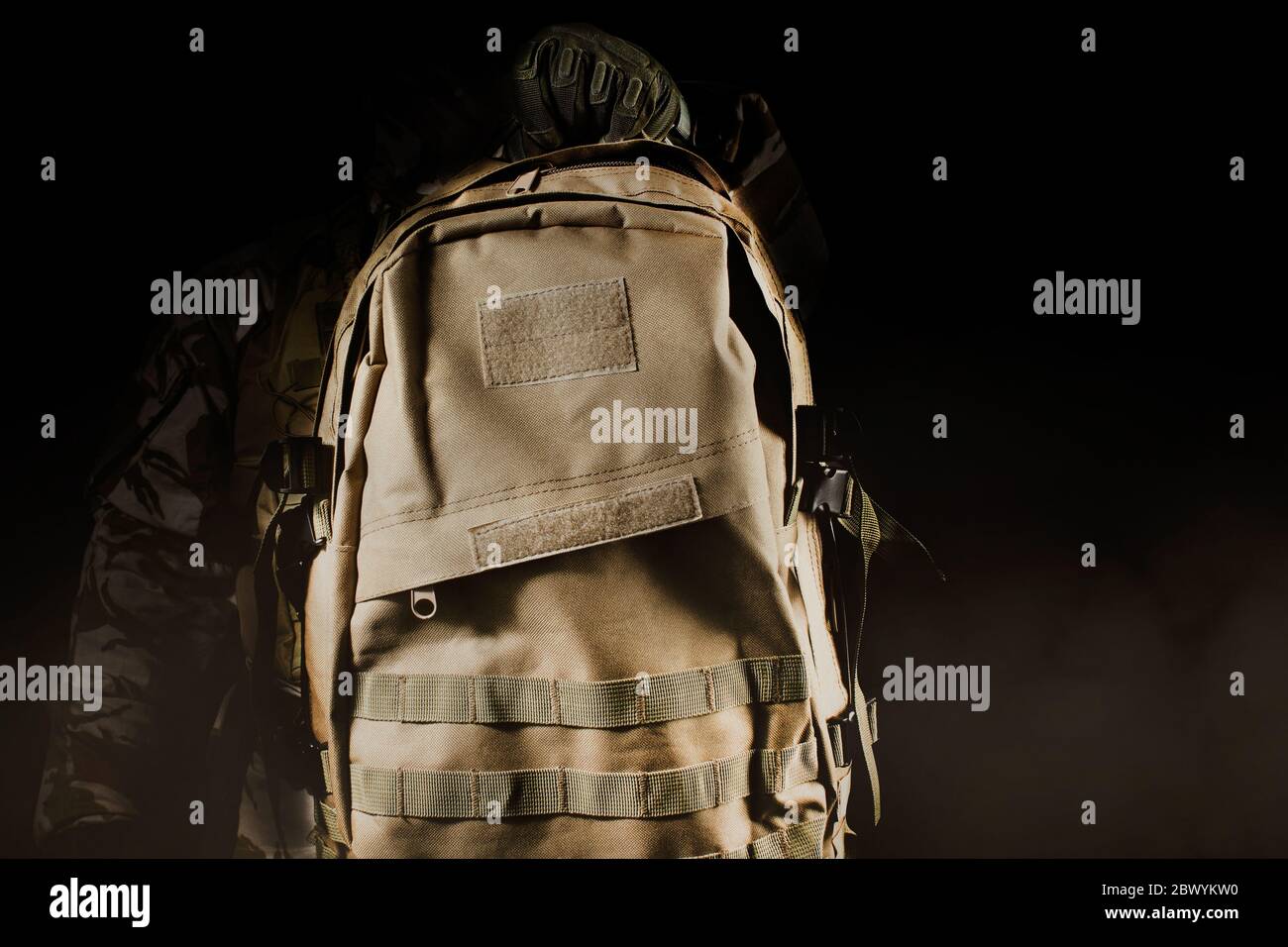 Foto eines voll ausgestatteten Soldaten in Uniform, Rüstung und Maske mit Rucksack auf dunklem Hintergrund mit Nebel und Staub Nahaufnahme. Stockfoto