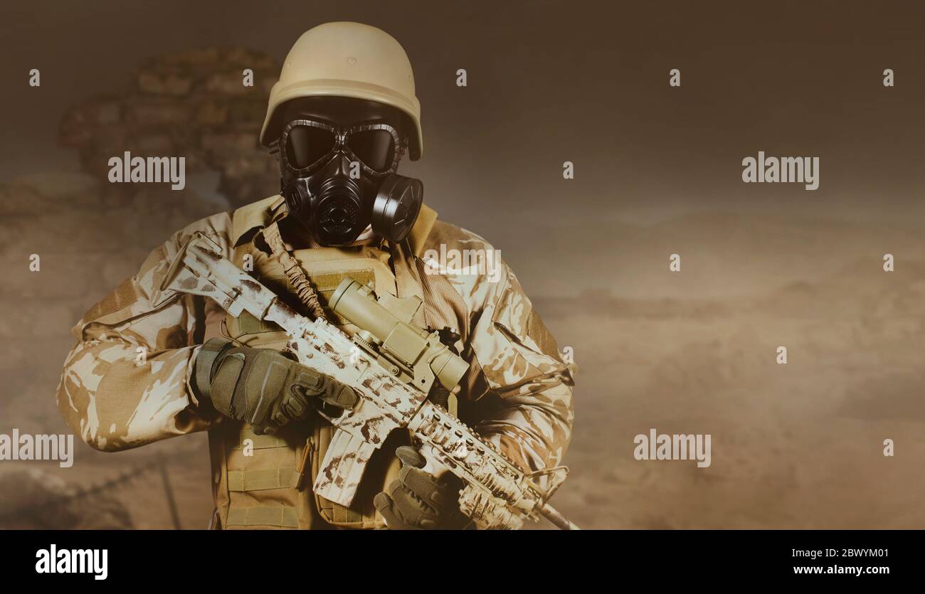 Foto eines voll ausgestatteten Soldaten in Uniform, Rüstung, Helm und Gasmaske mit Gewehr in düsteren Wüste Schlachtfeld Hintergrund stehen. Stockfoto