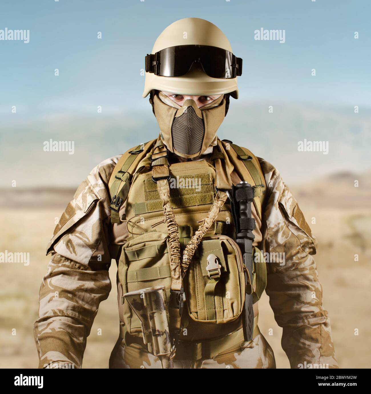 Foto eines voll ausgestatteten Soldaten in Uniform, Rüstung, Helm und Brille in der Wüste. Stockfoto