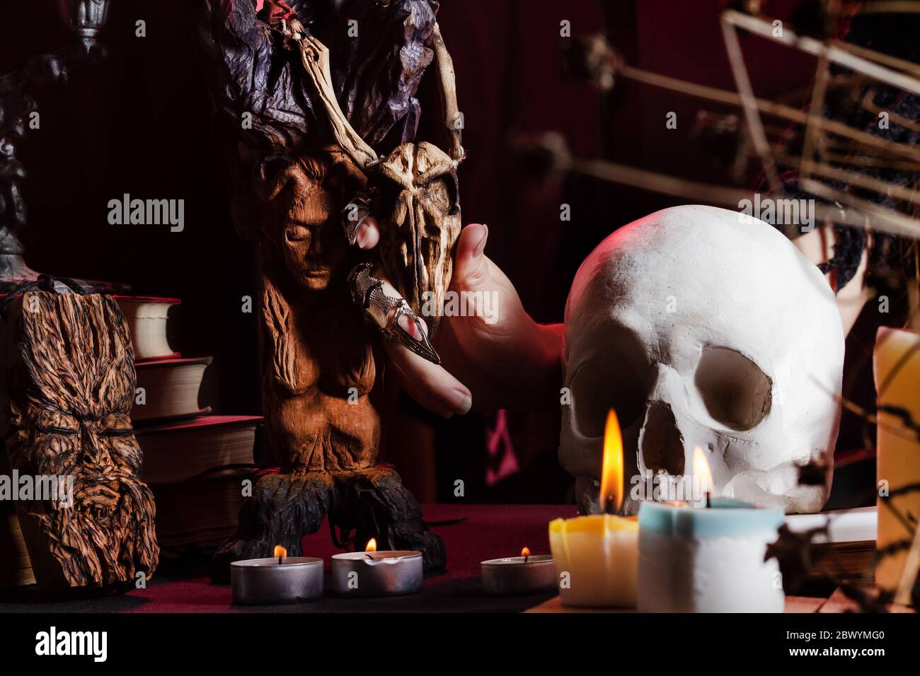 Foto einer weiblichen Hexenhand an einem Tisch mit Totenkopf, magischen  Amulette und Kerzen mit hölzernen Vogelschädel Stockfotografie - Alamy