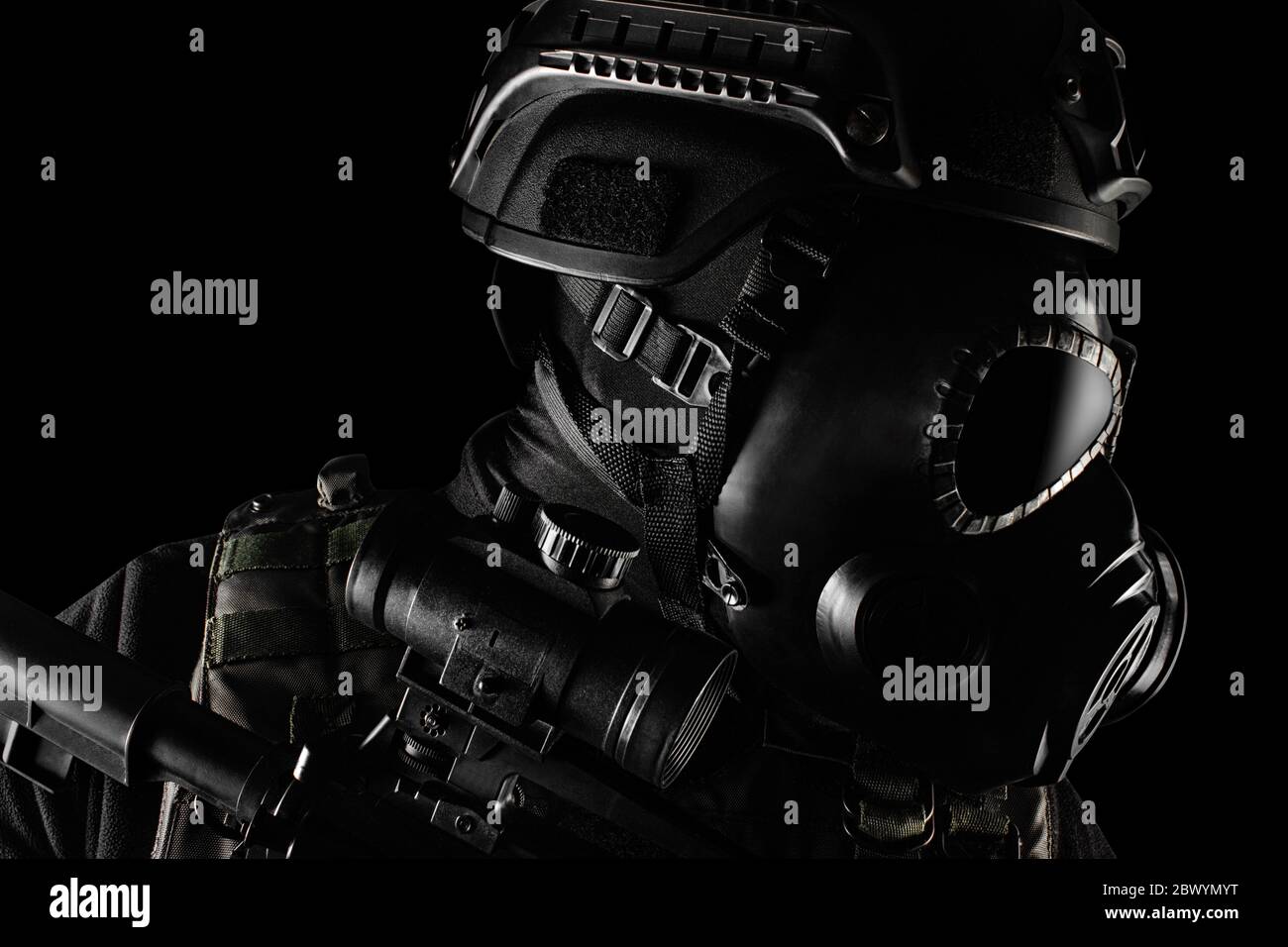 Foto eines voll ausgestatteten Soldaten in schwarzer Rüstung taktische Weste, Gasmaske, automatische Gewehr, Handschuhe und Helm auf schwarzem Hintergrund Nahaufnahme prof stehen Stockfoto