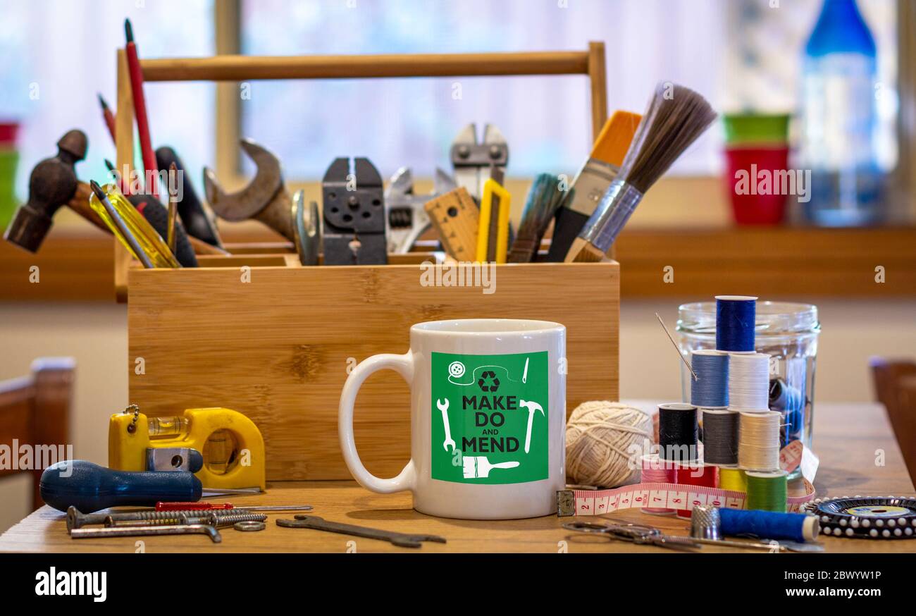 Make Do und flippen Logo auf Kaffeebecher umgeben von Werkzeugen auf Café-Tischplatte in Reparatur Café, Verbraucher Aktivismus, homespun Bewegung für nachhaltiges Leben Stockfoto