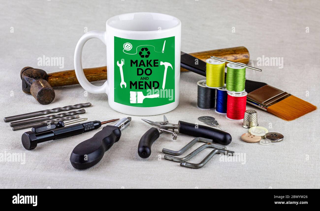 Make Do und flicken Logo auf Kaffeebecher umgeben von Werkzeugen auf Tischtuch, homespun Bewegung für nachhaltiges Leben und Abfall zu reduzieren. Stockfoto