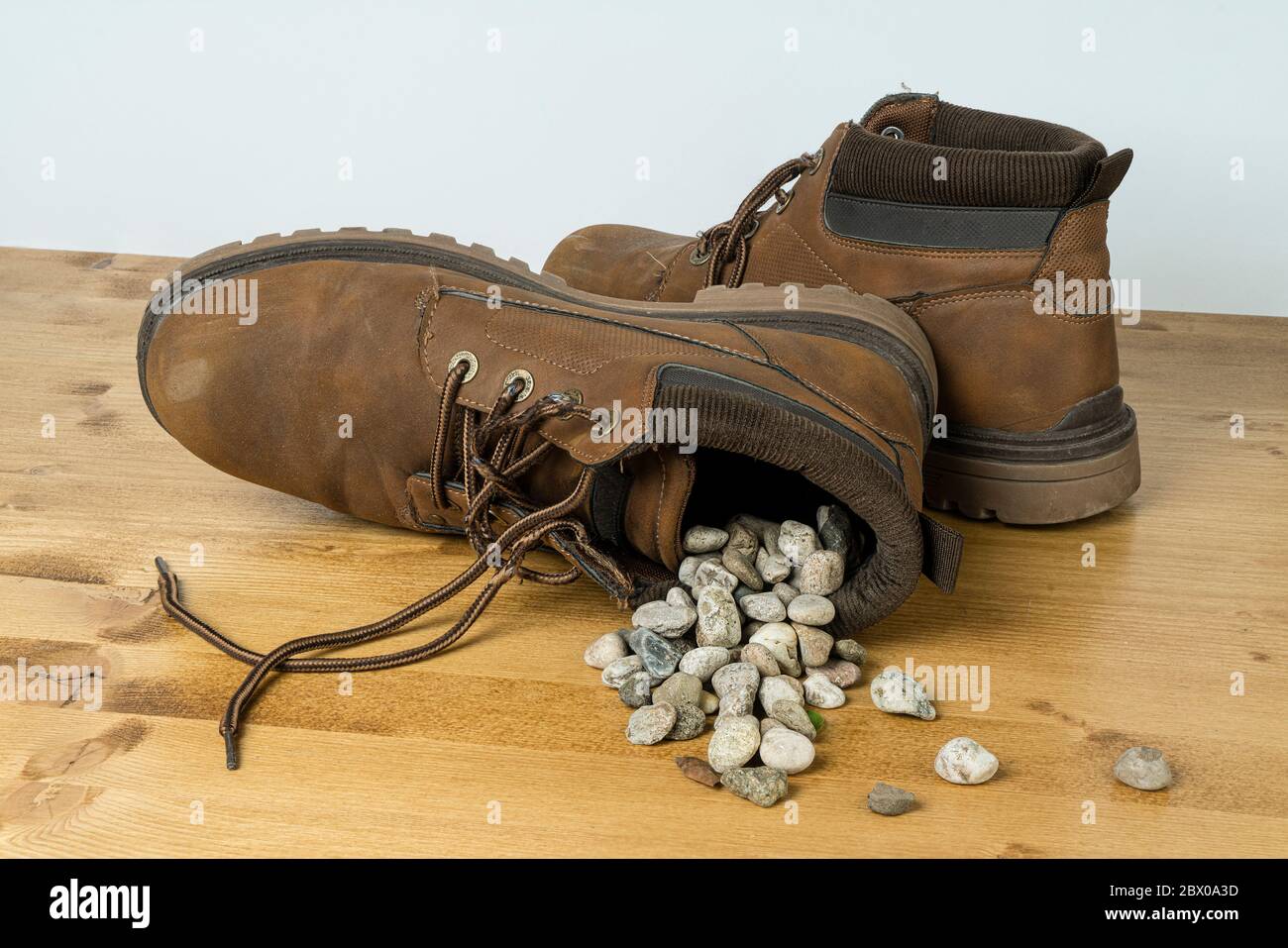 Ein Schuh voller Kies überdrehte sich auf einer Holzfläche Stockfoto