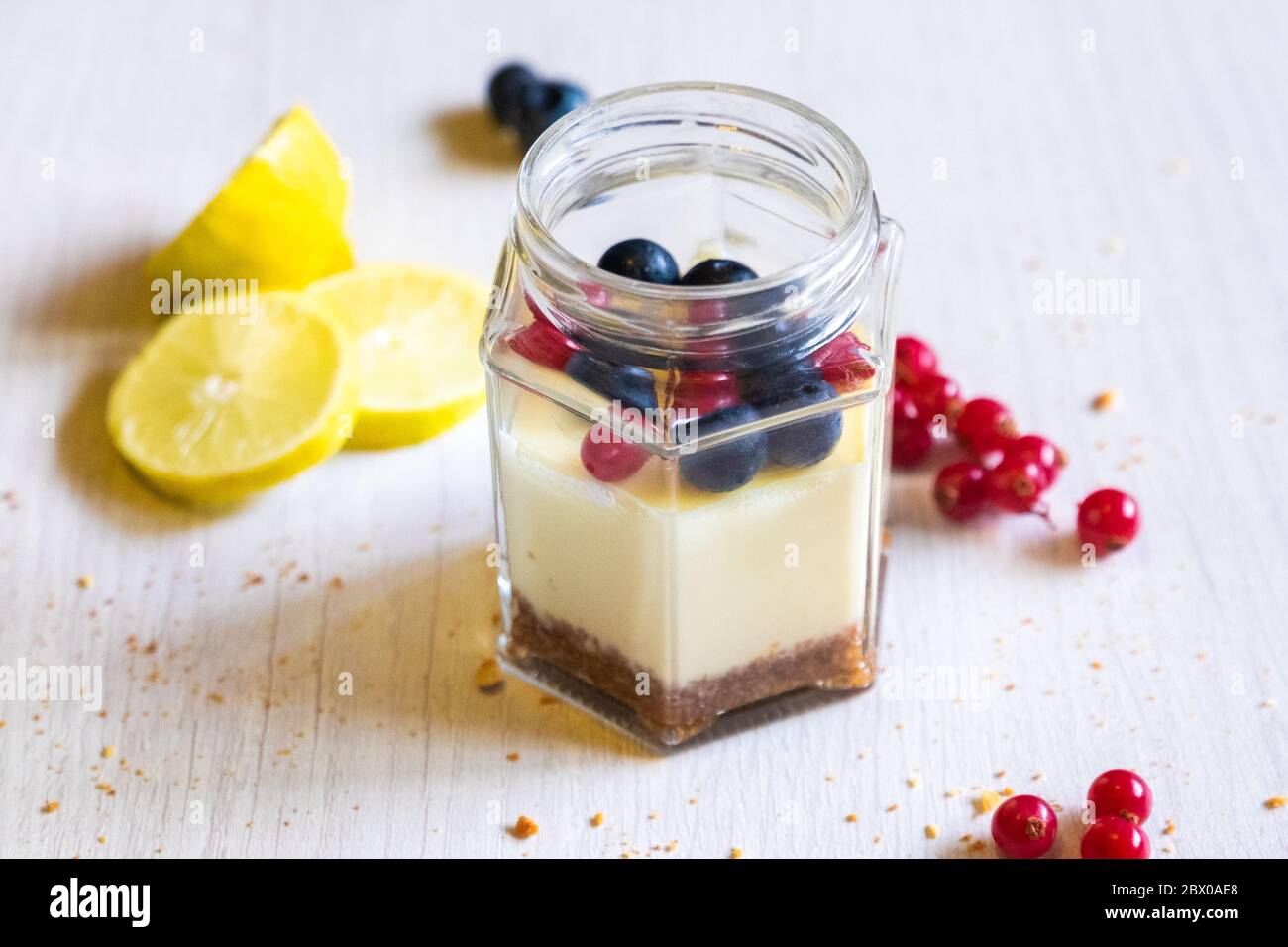 Sous Vide Käsekuchen in einem Glas, Dinner's Perspektive Foto mit Zitronenkeil und Beeren garnieren, heller Hintergrund. Stockfoto