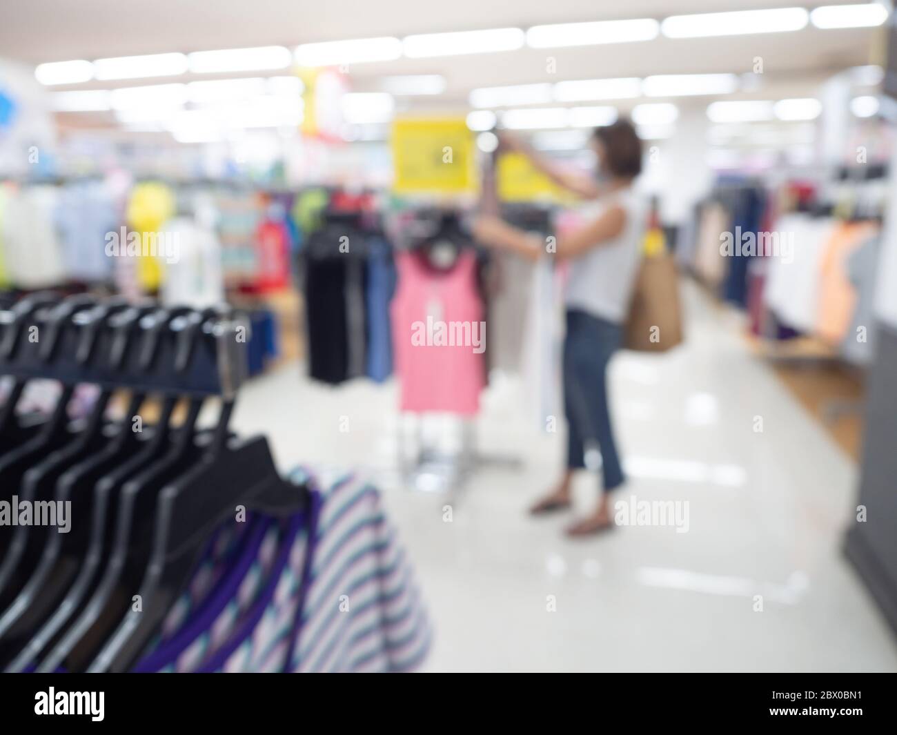 Supermarkt verwischen Hintergrund. Verschwommene Shopping-Frau mit hängenden Kleidern im Einkaufszentrum. Stockfoto
