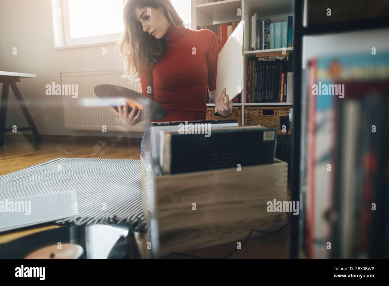 Junge Frau auf dem Boden mit Schallplatte sitzend. Musik auf dem Plattenteller, Freizeit, Hobbie Stockfoto