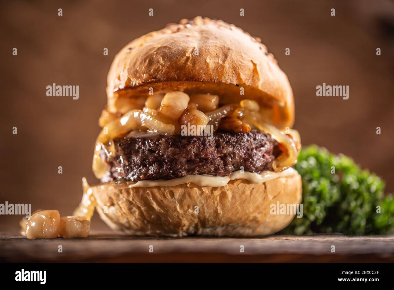 Rinderburger mit geschmolzenem Käse, karamellisierte Zwiebeln in einem Sesambrötchen Stockfoto