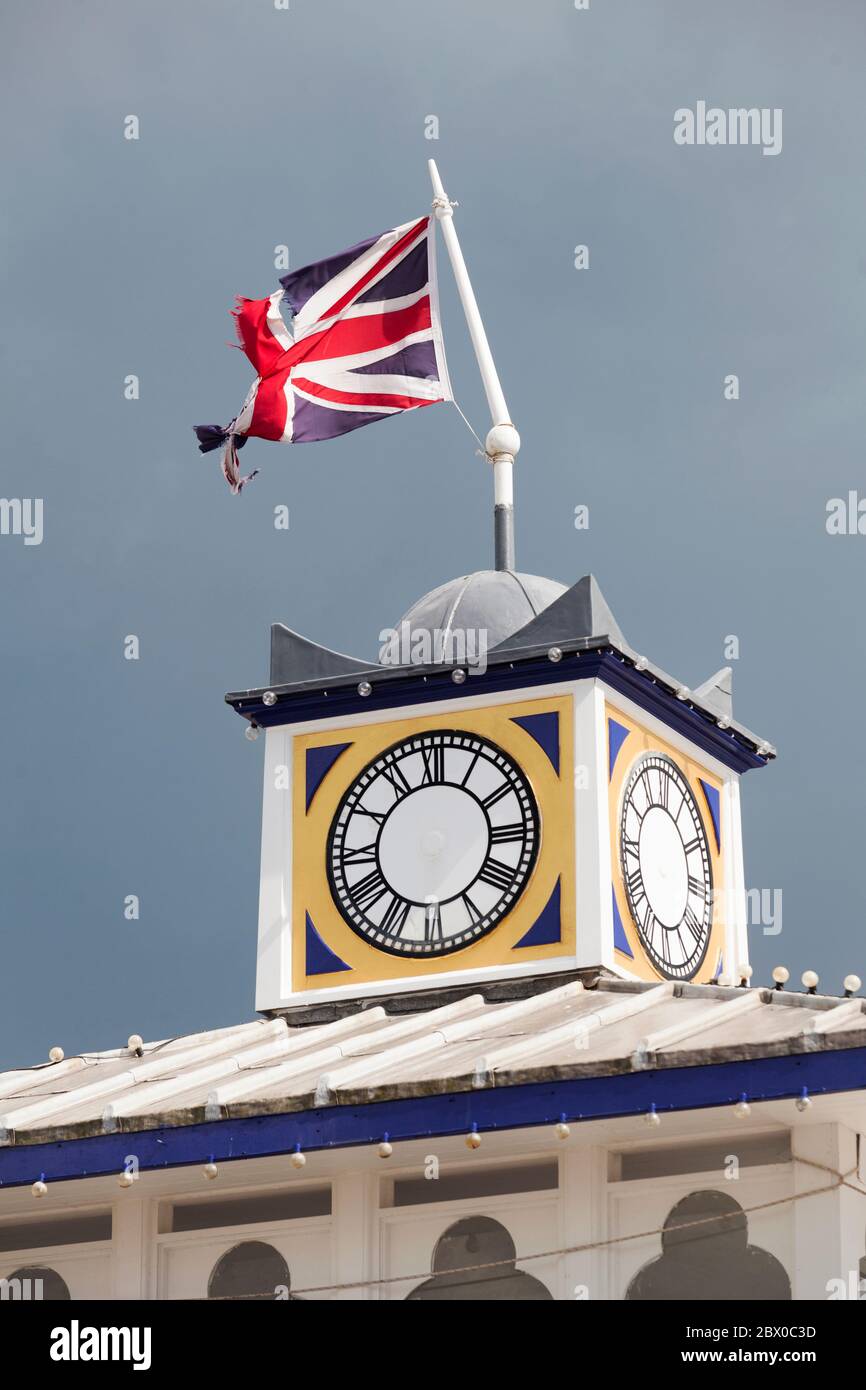 Farbfoto eines beschädigten Union Jack Flagge und Turm Uhr am Eastbourne Pier. Stockfoto