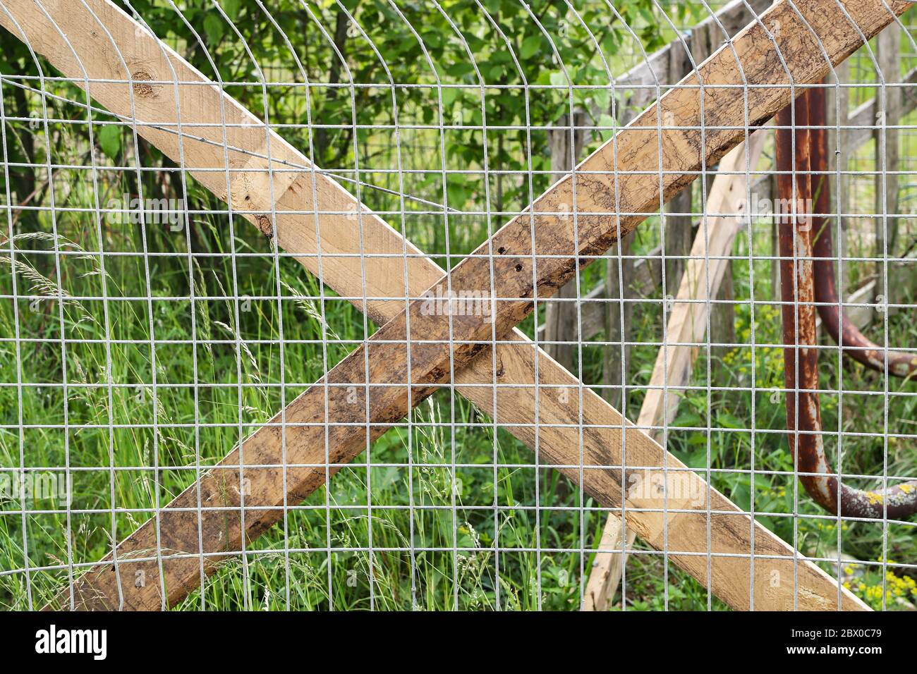 Zaun aus Metall-Mesh durch Bretter befestigt Stockfoto