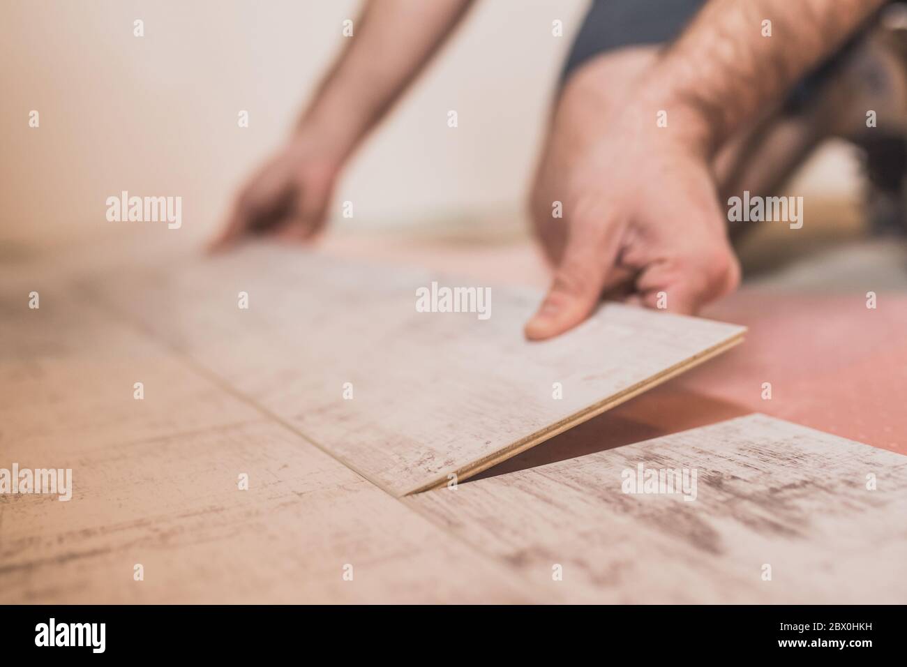 Nahaufnahme der Hand des Meisters verbindet Laminatschloss beim Verlegen von Bodenbelägen Stockfoto