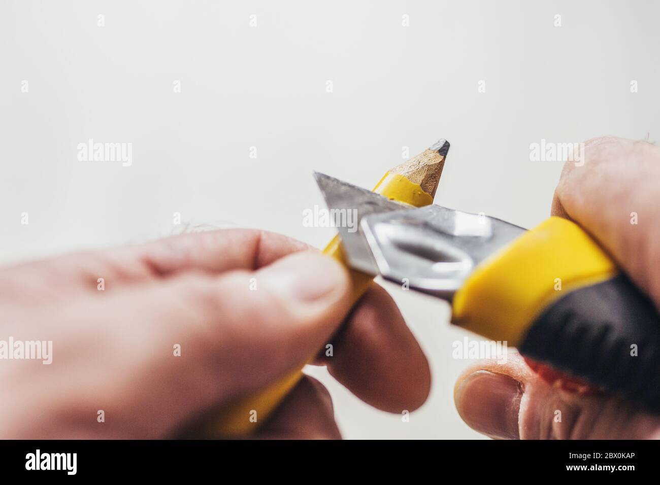 Die Hand schärfen den Bleistift mit dem Papiermesser - die Sicht der ersten Person Stockfoto