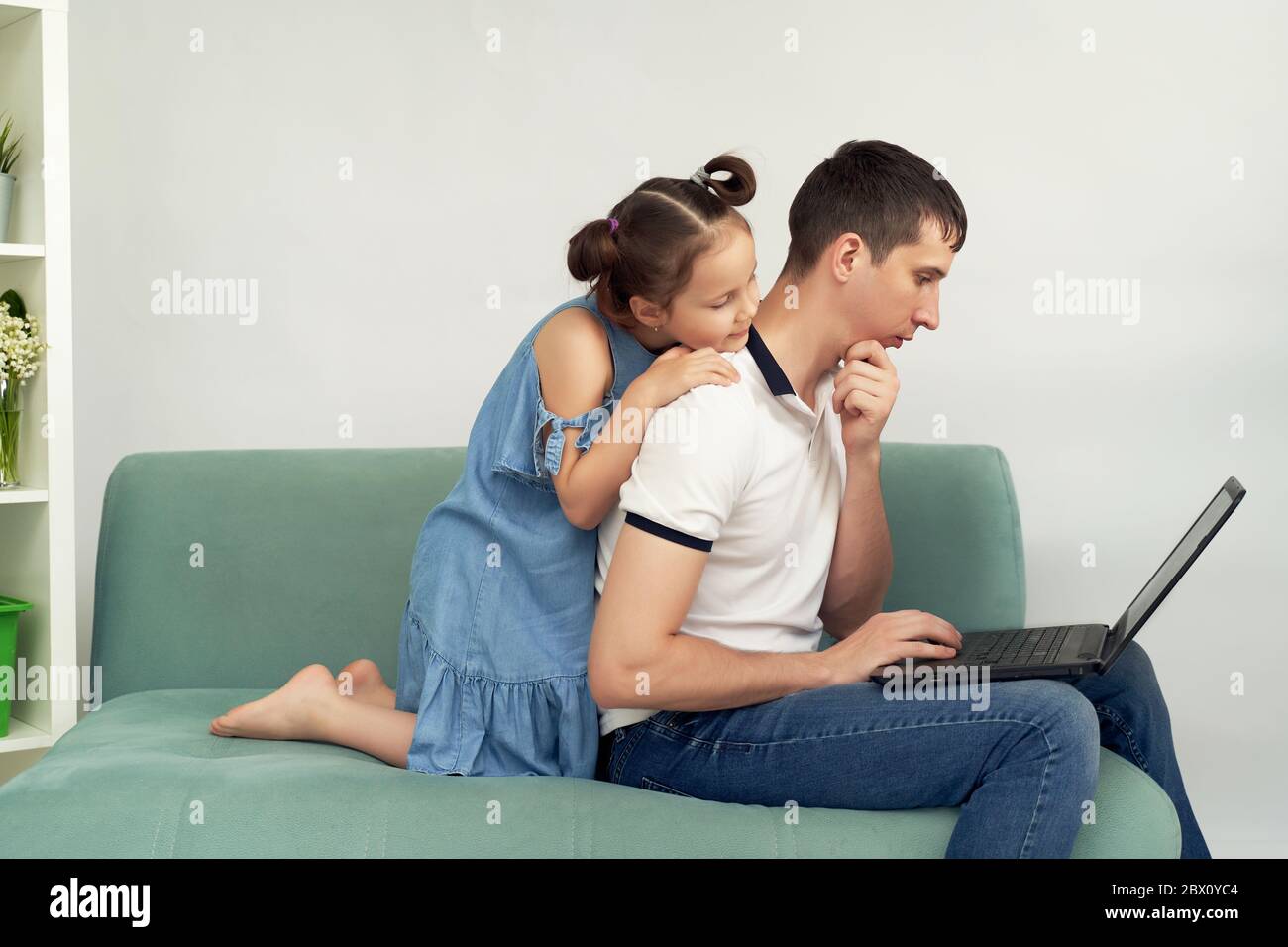 Freiberuflicher Mitarbeiter, der zu Hause unter angenehmen Bedingungen arbeitet. Mann versucht zu arbeiten, Kind verhindert seinen Vater zu arbeiten. Stockfoto