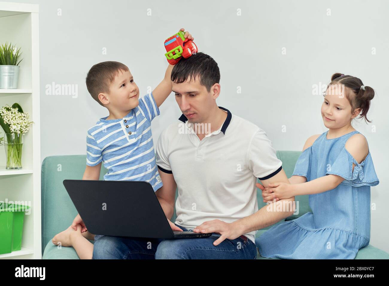 Freiberuflicher Mitarbeiter, der zu Hause unter angenehmen Bedingungen arbeitet. Mann versucht zu arbeiten, Kind verhindert seinen Vater zu arbeiten. Stockfoto