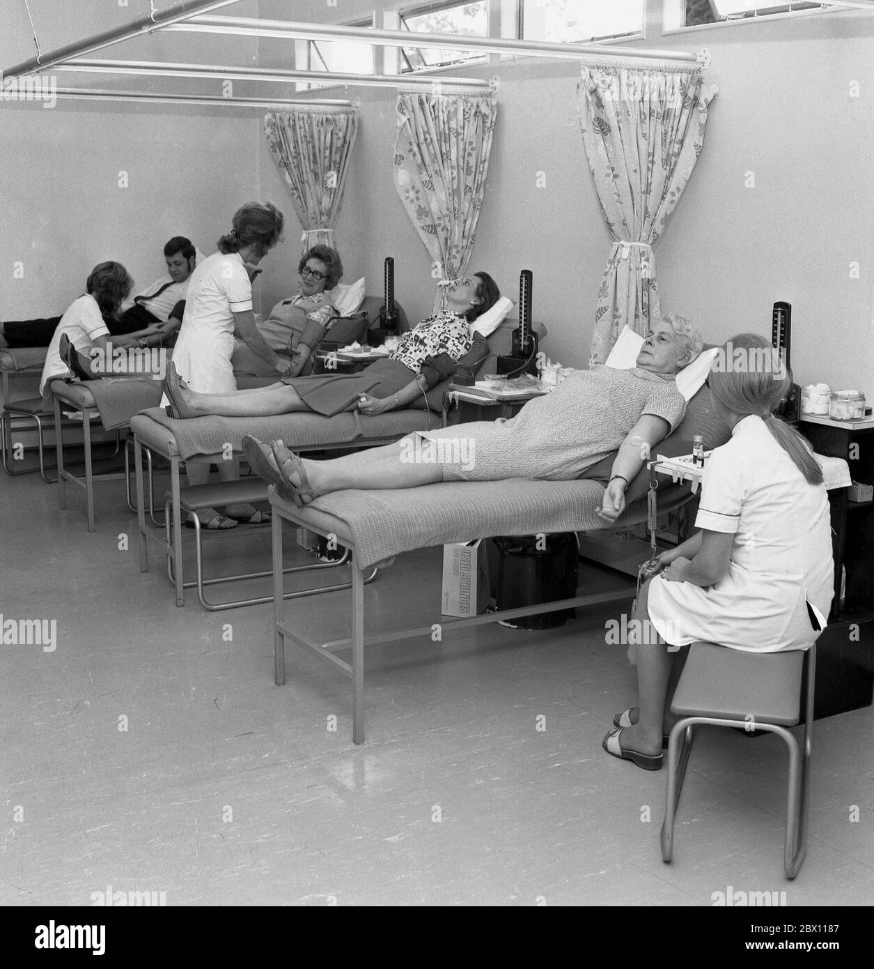 „Blutspender“, Mitglieder der Öffentlichkeit, die in einem medizinischen oder medizinischen Zentrum freiwillig auf chirurgischen Betten liegen und Blut spenden, Lewisham, South London, Ende der 60er, Anfang der 70er Jahre. Blut für die Versorgung der Gemeinschaft zu geben, ist ein öffentlicher Akt, der von Menschen getragen wird, da Blut Leben retten kann. Stockfoto