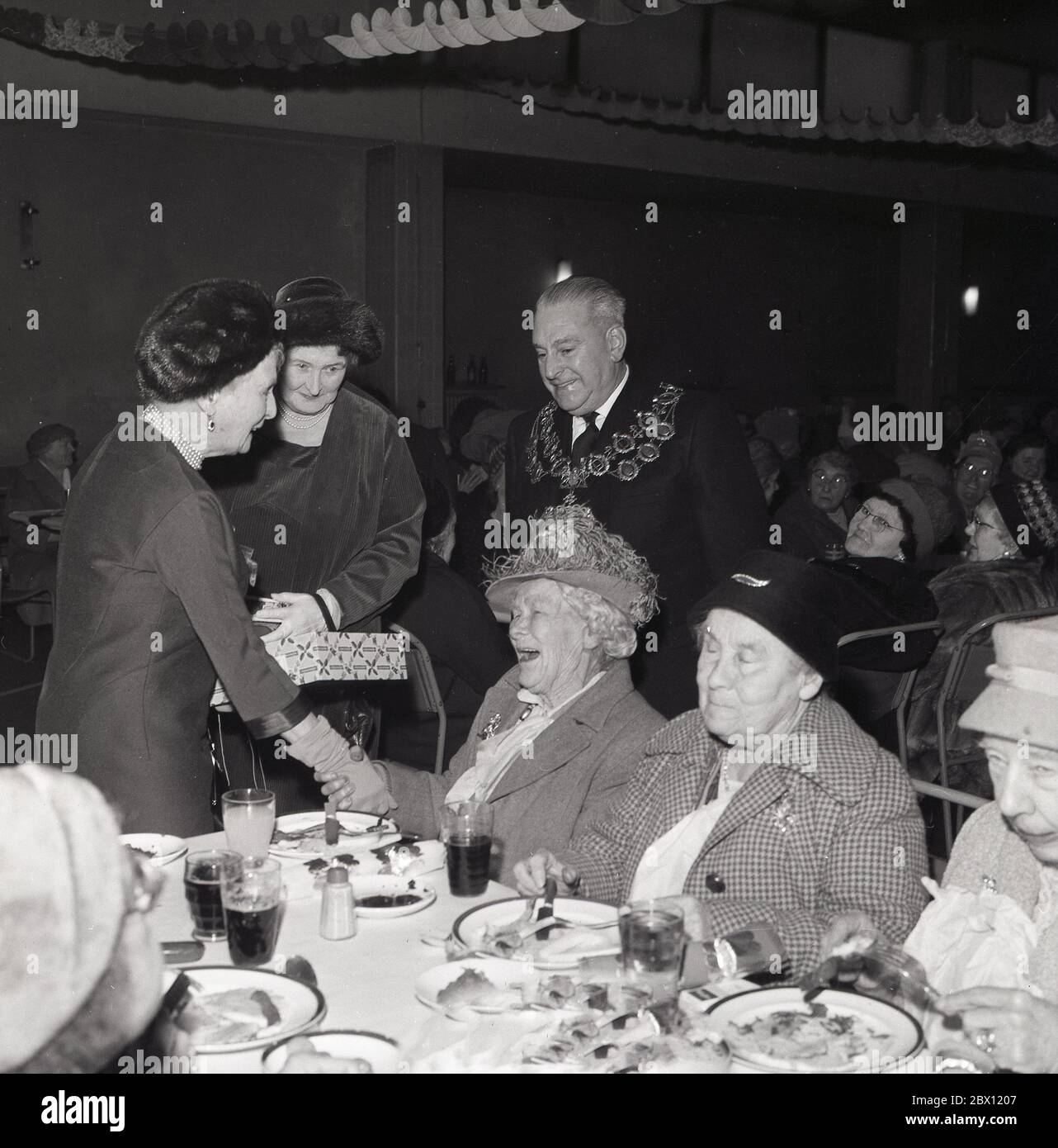 Die 60er Jahre, historisch, bei einem Weihnachtsessen der alten Leute im Rathaus, eine Überraschung für die Gäste, als eine entzückte alte Dame schüttelt die Hände einer königlichen Besucher, Prinzessin Alice begleitet von der Bürgermeister auf einem königlichen Besuch in der Gemeinde Lewisham, South London, England, Großbritannien. Prinzessin Alice von Battenberg wurde 1885 im Schloss Windsor geboren und war die Mutter von Prinz Philip, dem Ehemann der Königin Elizabeth II.. Stockfoto