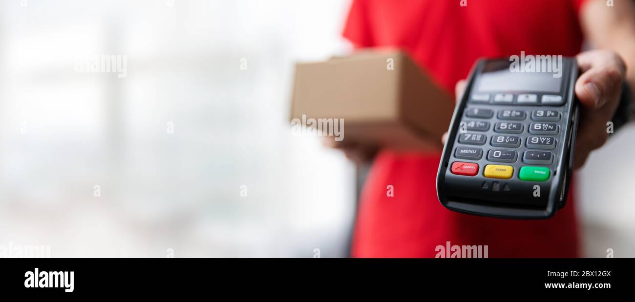 Lieferung Zahlung - Kurier mit Paket und POS-Terminal in der Hand mit Kopierraum Stockfoto