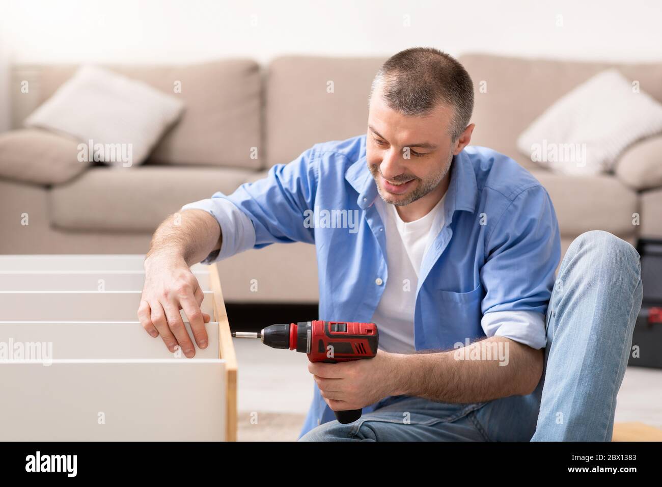 Mann Befestigung Möbel Reparatur Schrank Mit Elektrischen Bohrer Zu Hause Stockfoto