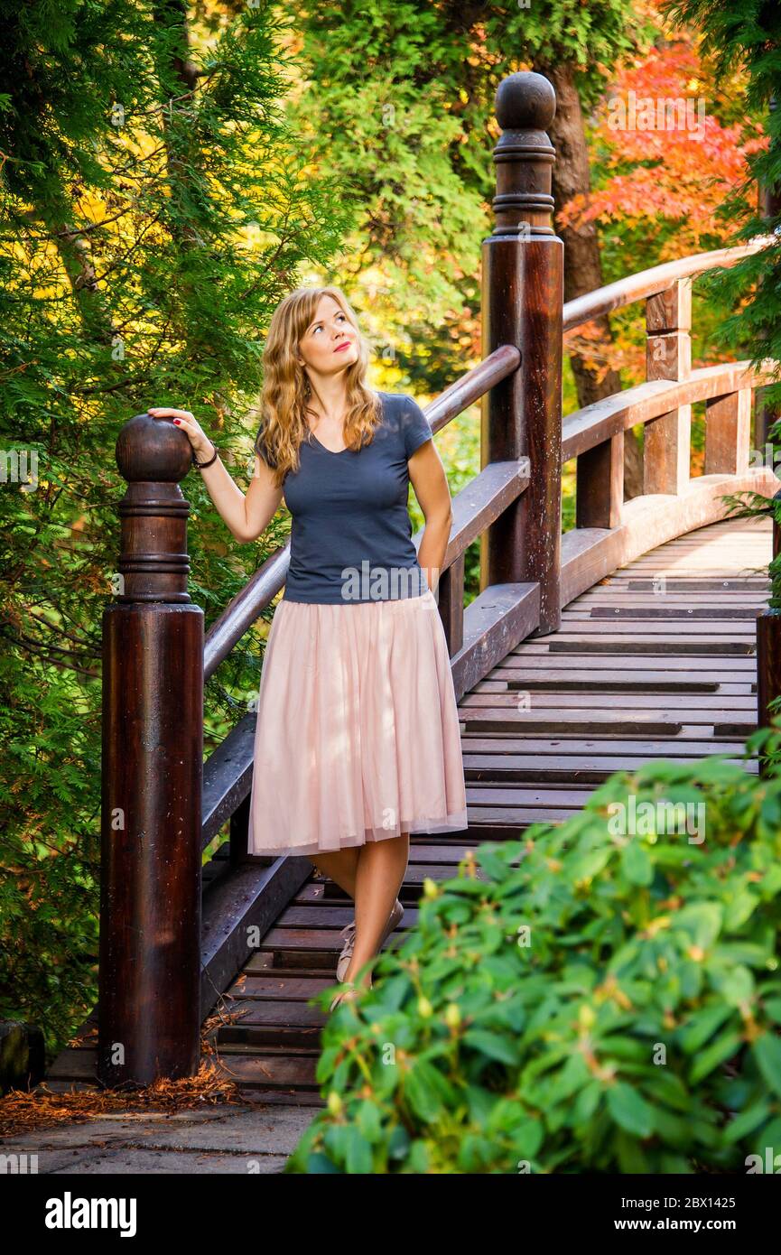 Wunderende junge blonde Frau auf einer Holzbrücke im Herbst japaneese Garten Stockfoto
