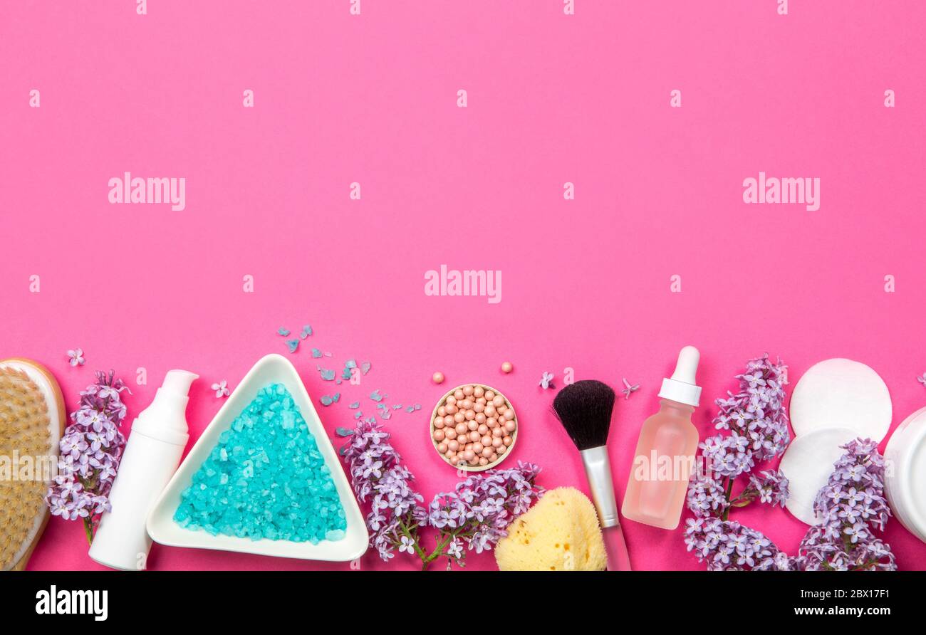 Flache Ansicht von verschiedenen weißen Kosmetik- und Kosmetikprodukten Behälter mit Fliederblüten (Syringa) auf rosa Studiohintergrund. Unterer Rand. Stockfoto