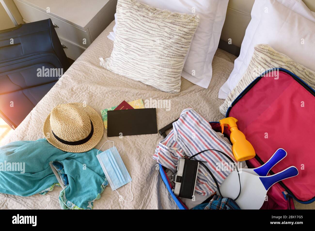 Sommerurlaub Reise-Accessoires auf dem Bett und Maske für Urlaubsreisen in Coronavirus Saison im Schlafzimmer vorbereitet. Draufsicht Stockfoto