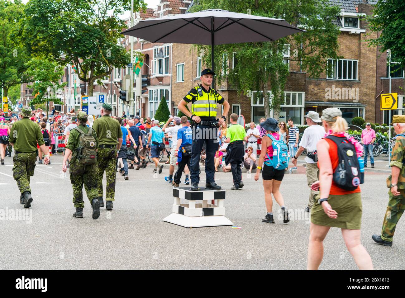 Nijmegen Juli 19 2017: 4-tägige Teilnehmer des Walking Turniers, die einen Polizisten auf dem Weg zum Ziel des ersten Tages passieren Stockfoto