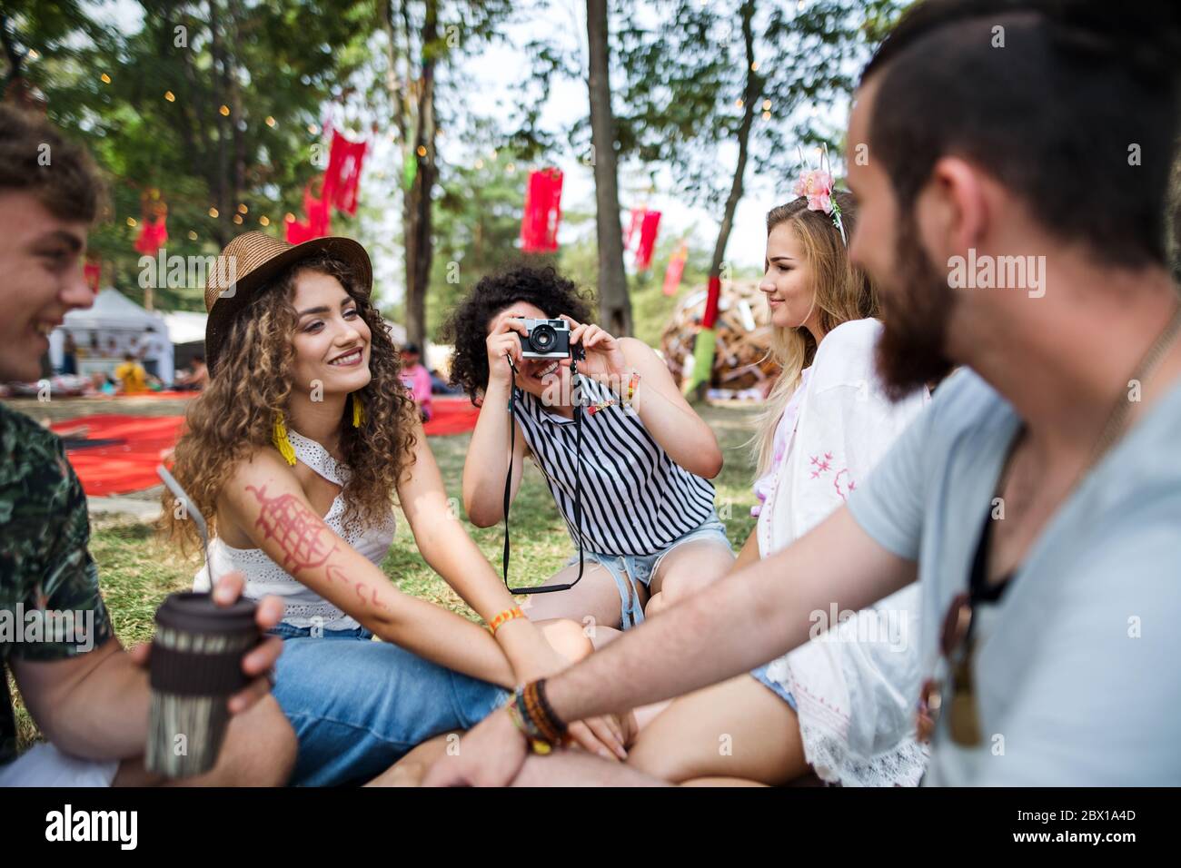 Gruppe von jungen Freunden sitzen auf dem Boden beim Sommerfest, fotografieren. Stockfoto